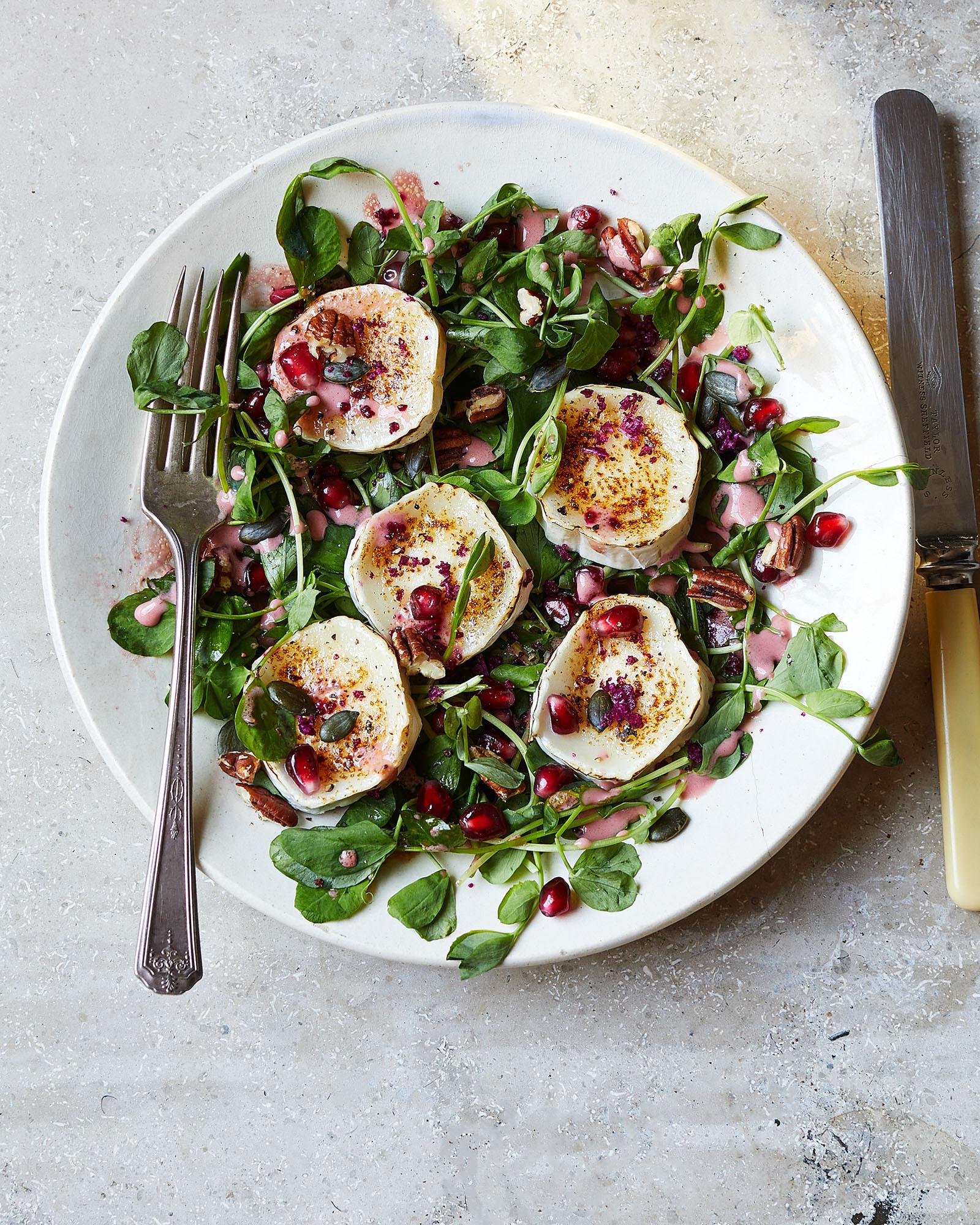 A plate featuring grilled halloumi cheese, pomegranate seeds, and pink dressing.