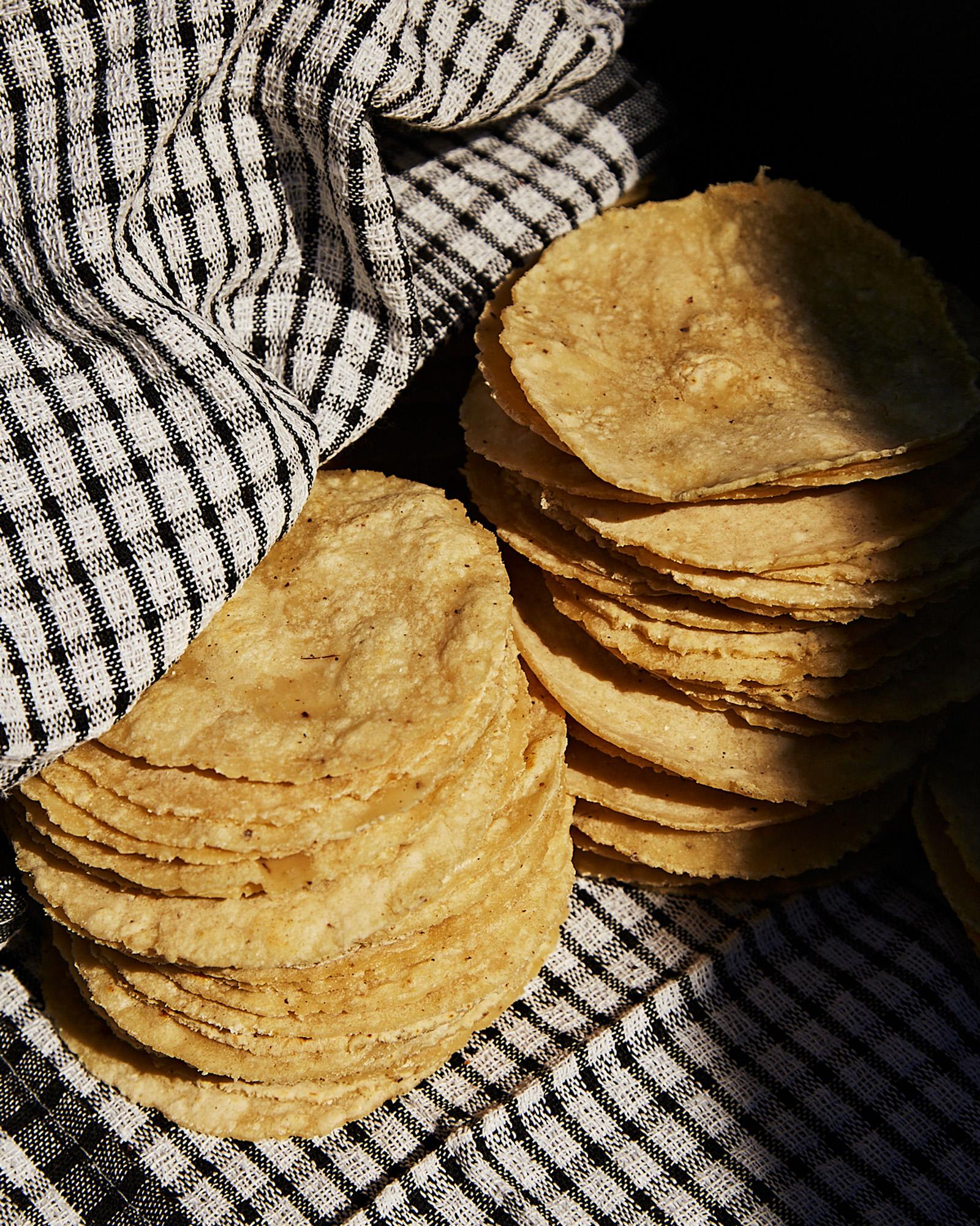 A stack of corn tortillas on a checkered cloth.