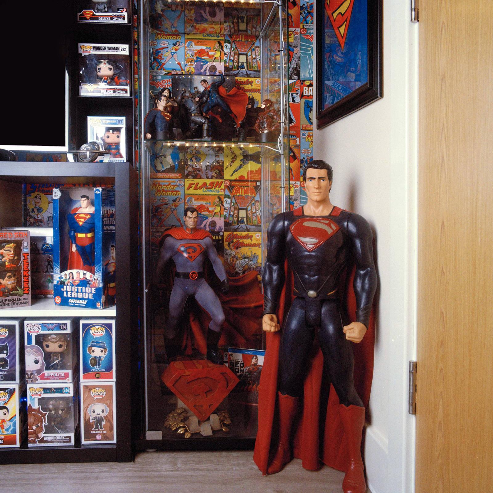 A collection of Superman and DC Comics items displayed in a glass cabinet and on shelves.