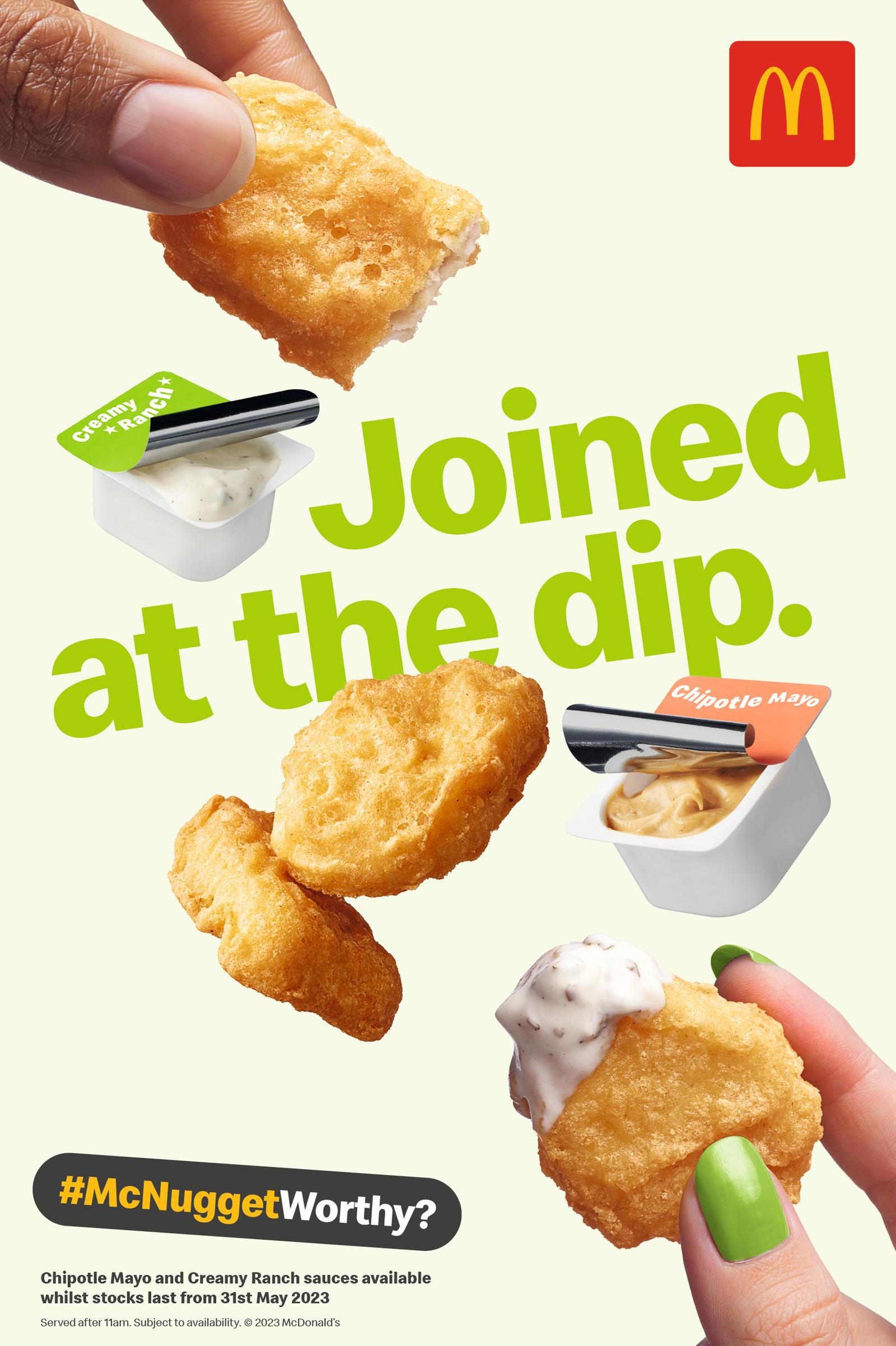 A hand holds a McDonald's McNugget with dipping sauce.