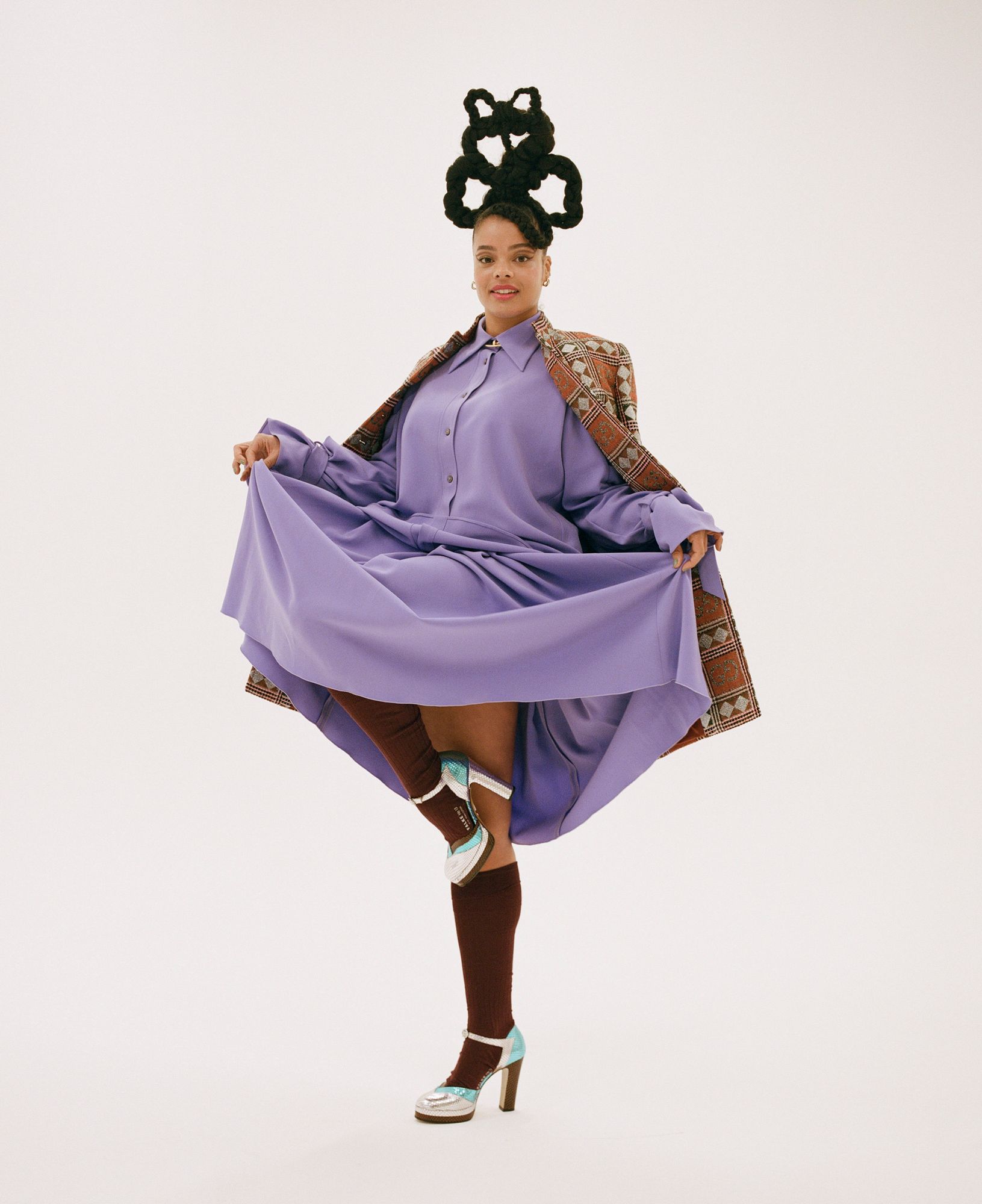 A woman with a unique hairstyle and a purple dress, posing for a portfolio photo shoot.