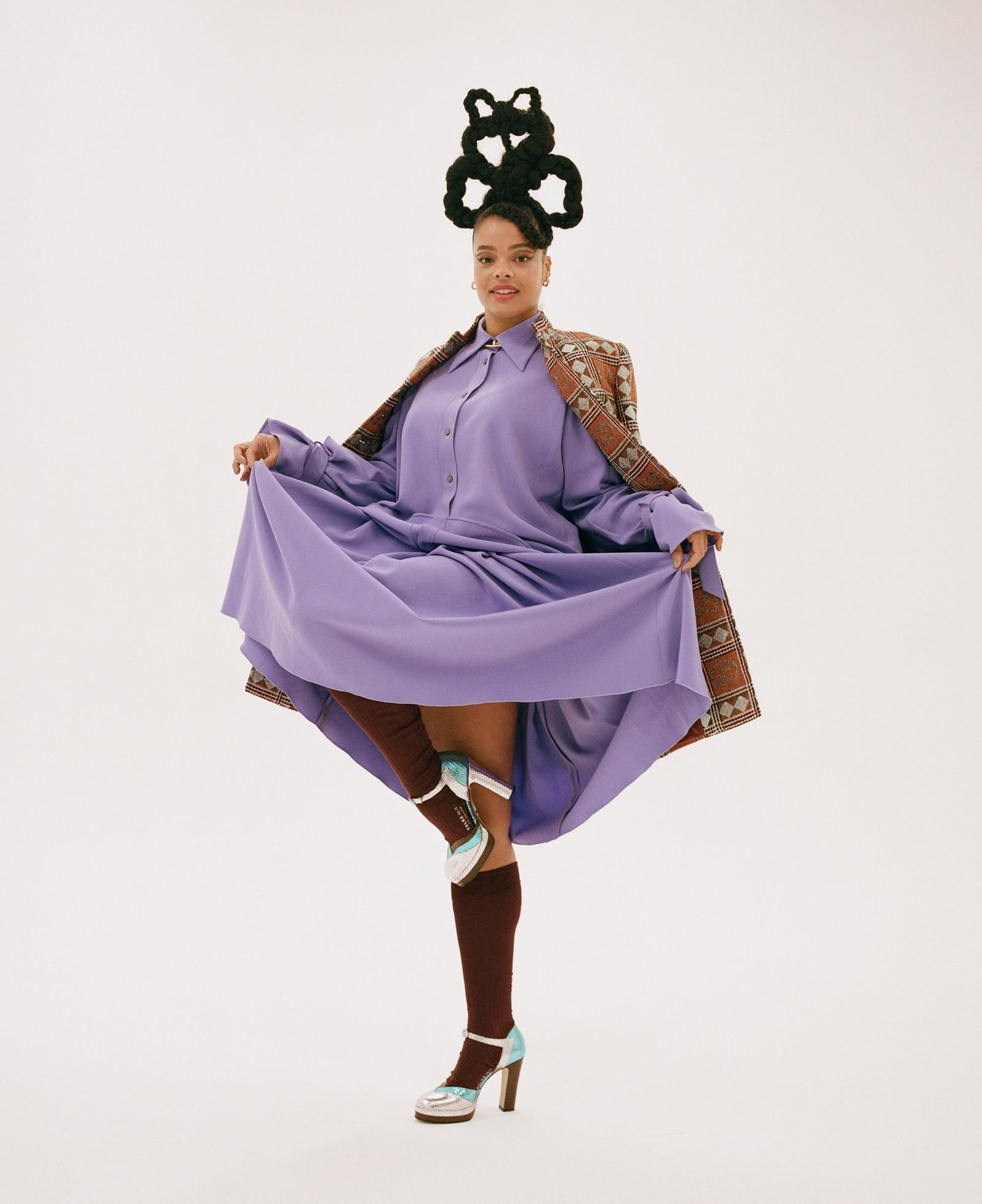A woman with a unique hairstyle and a purple dress, posing for a portfolio photo shoot.