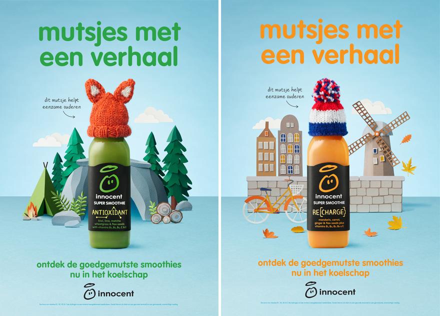 Two bottles of Innocent smoothie with different flavors, one with a fox hat and the other with a Dutch flag hat, in a landscape with trees, a campfire, and a windmill.