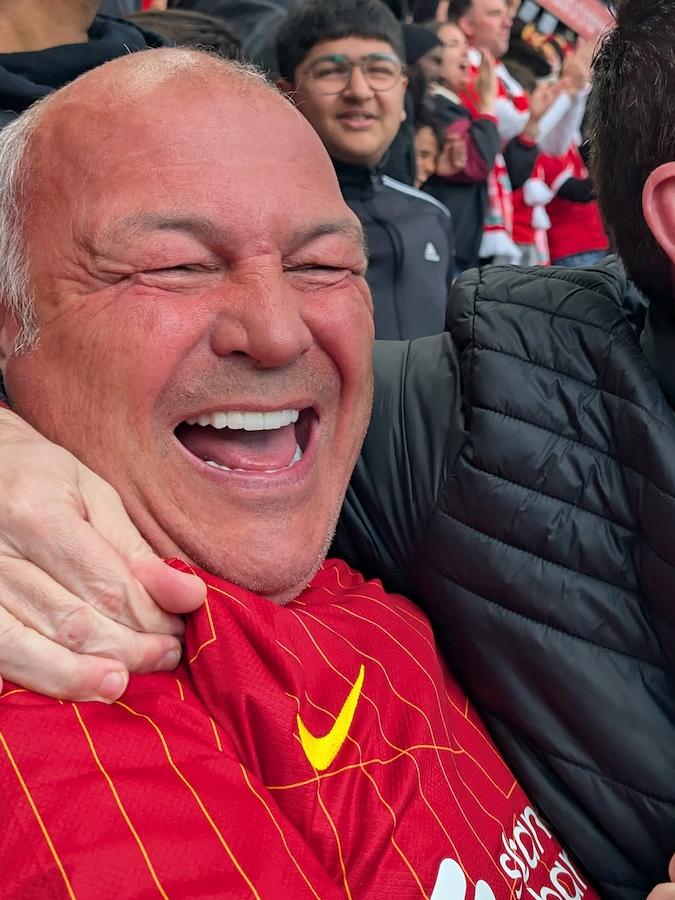 Two men smile and embrace in a football stadium.