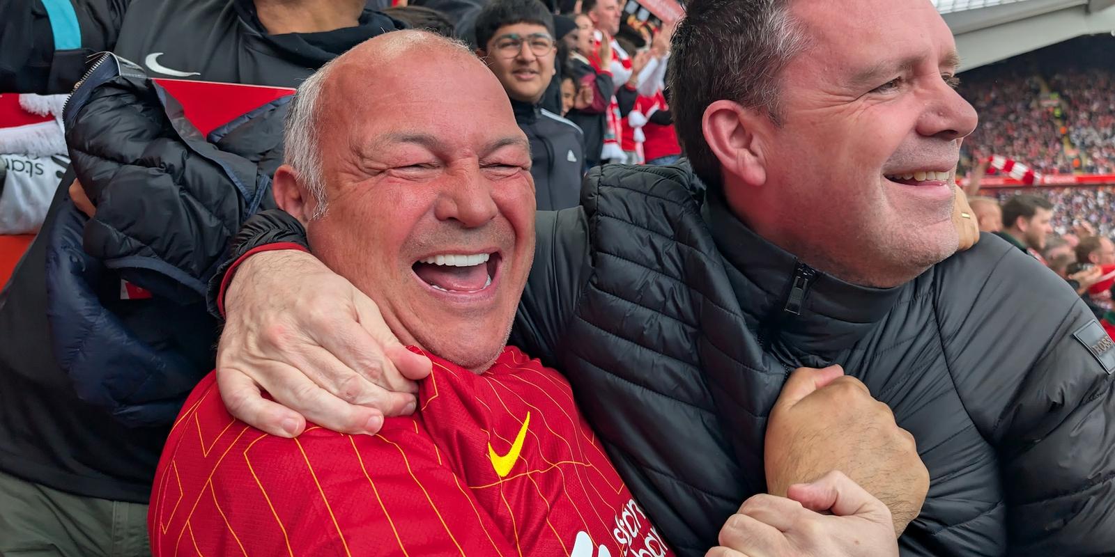 Two men smile and embrace in a football stadium.