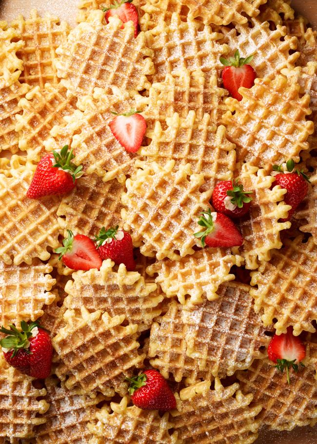 A plate of waffles topped with strawberries and powdered sugar.