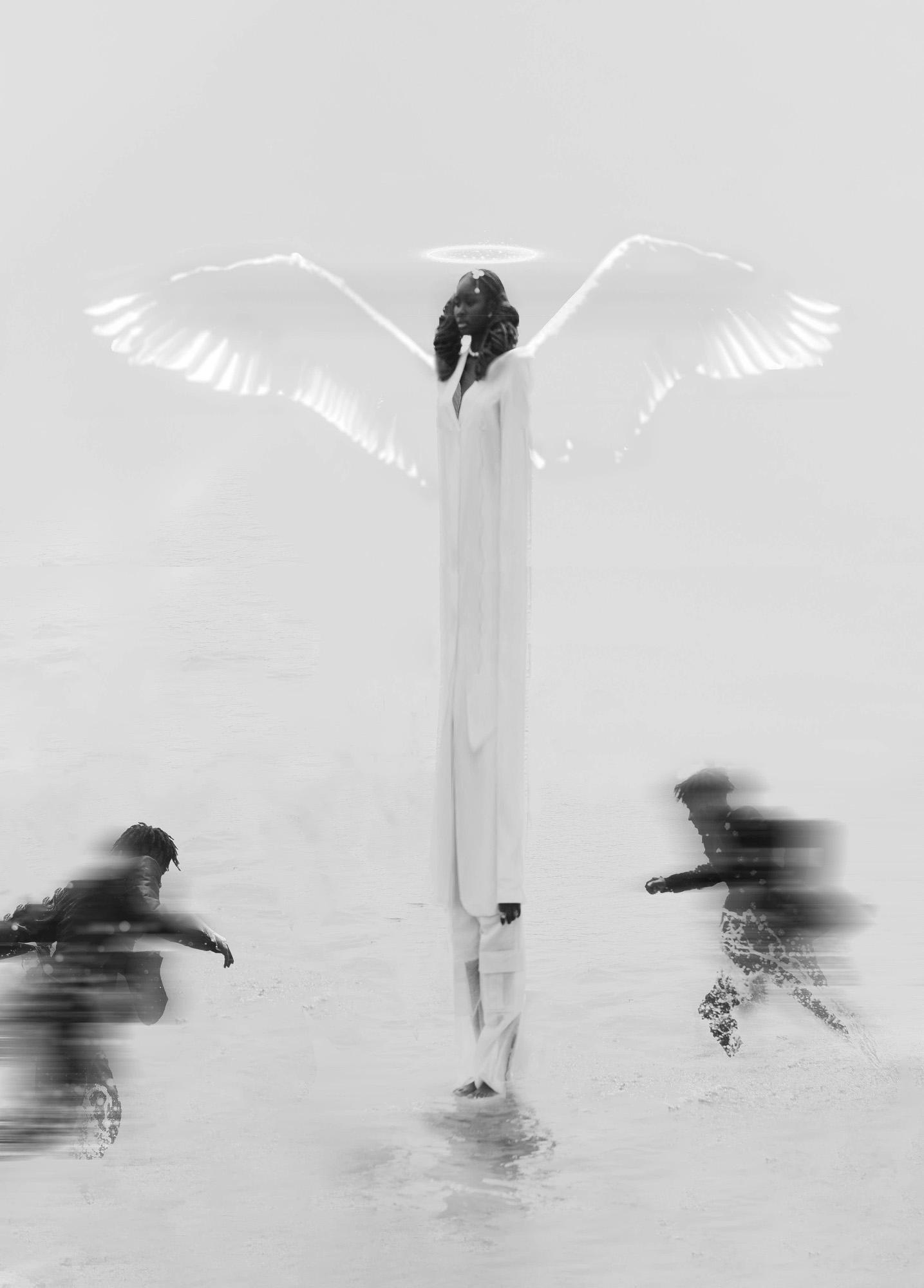 A woman in an angel costume stands on a beach with two people in the background.