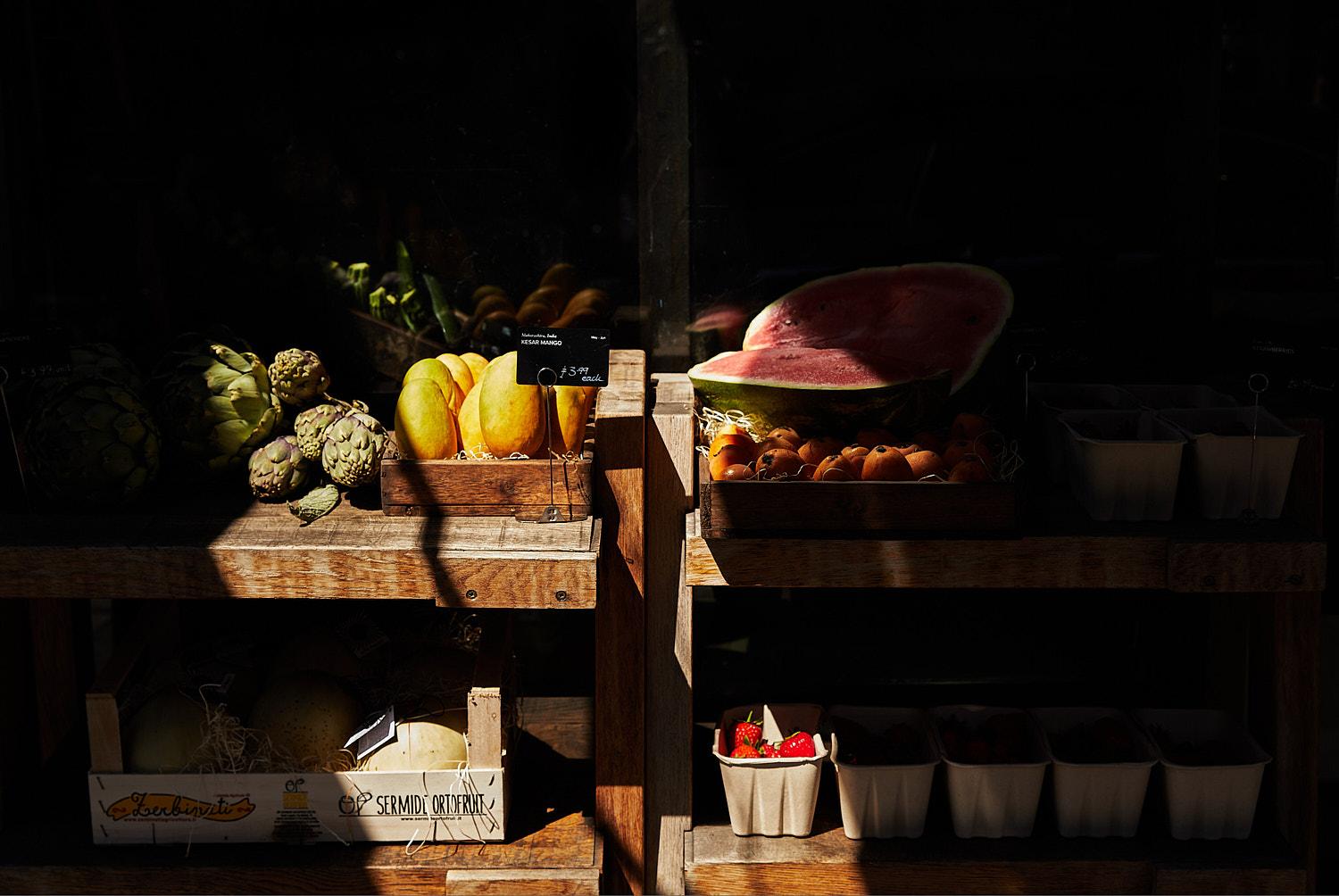 Various fruits and vegetables arranged on a wooden table in a dark, rustic setting.