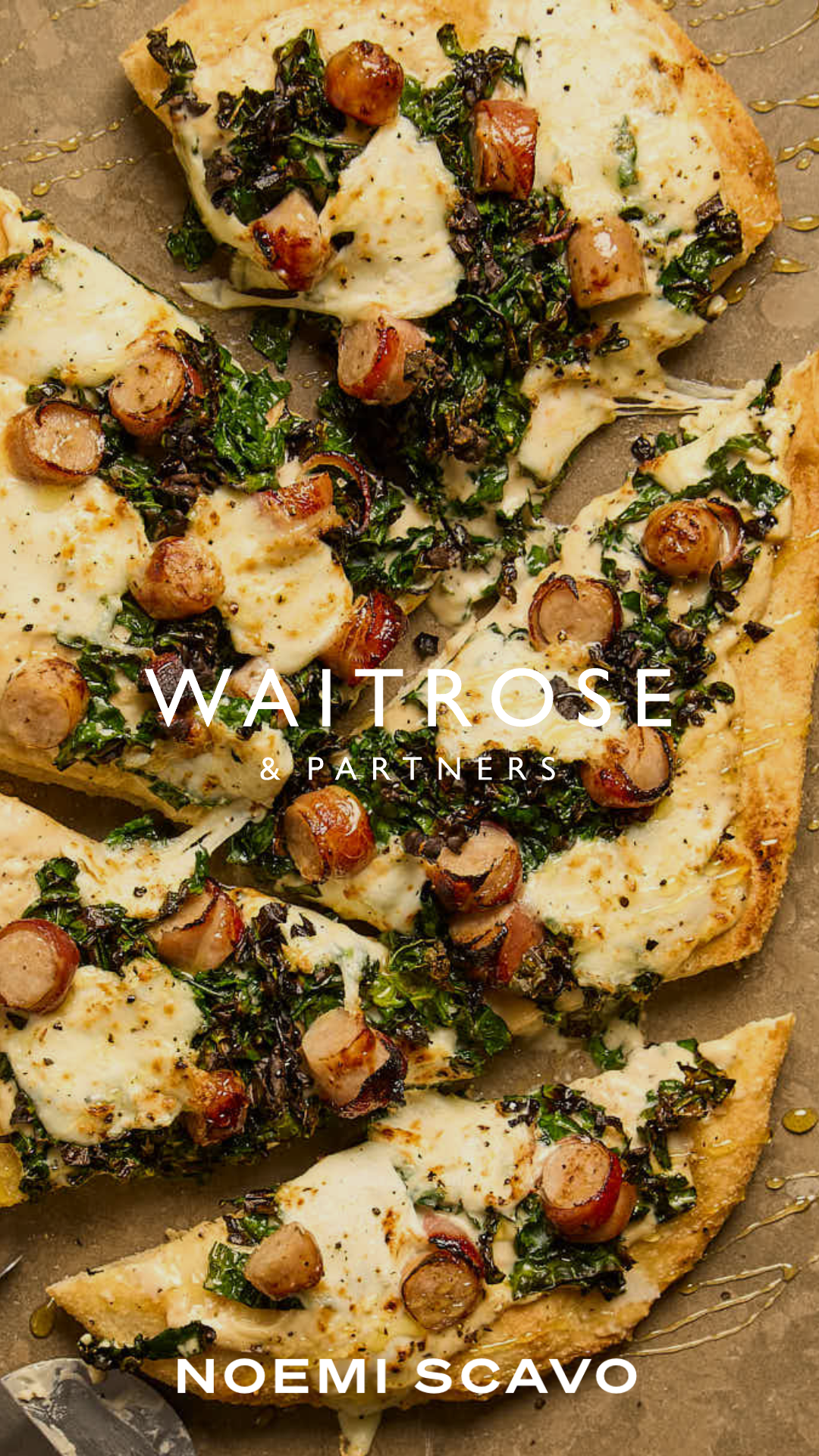 The image shows a close-up, overhead view of a rustic pizza topped with melted white cheese, dark leafy greens, and sliced sausages. The pizza is presented on a textured brown surface with a drizzle of honey or oil, featuring the "Waitrose & Partners" logo and Noemi Scavo's name.