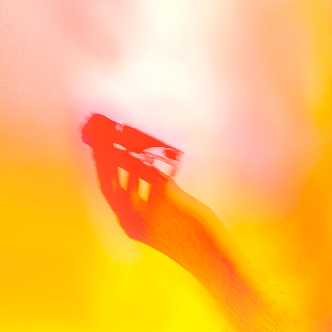 A hand holding a smartphone, with a blurred background and a bright, sunny atmosphere.