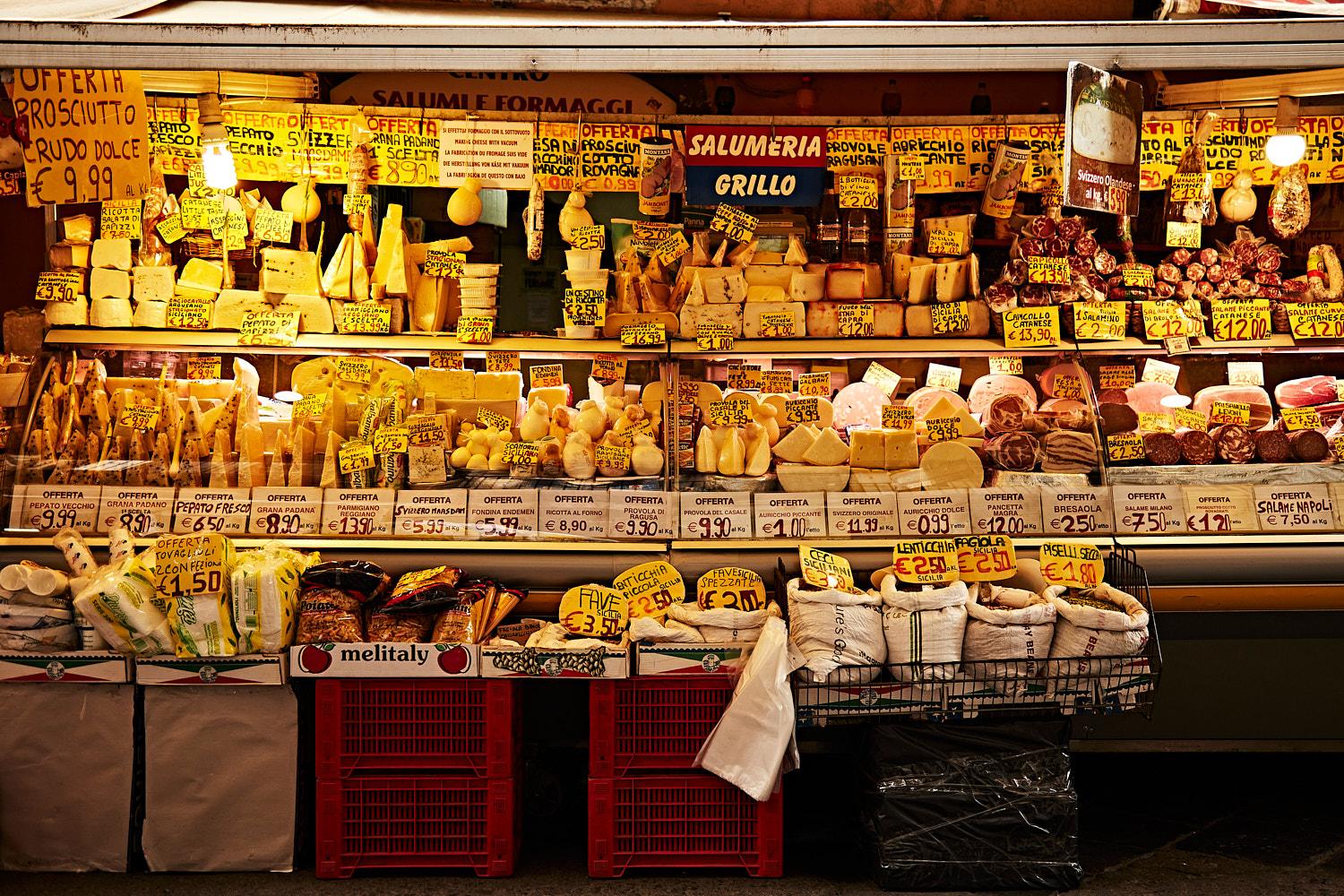 A bustling market scene featuring various foods and produce like cheese, meat, and bread.