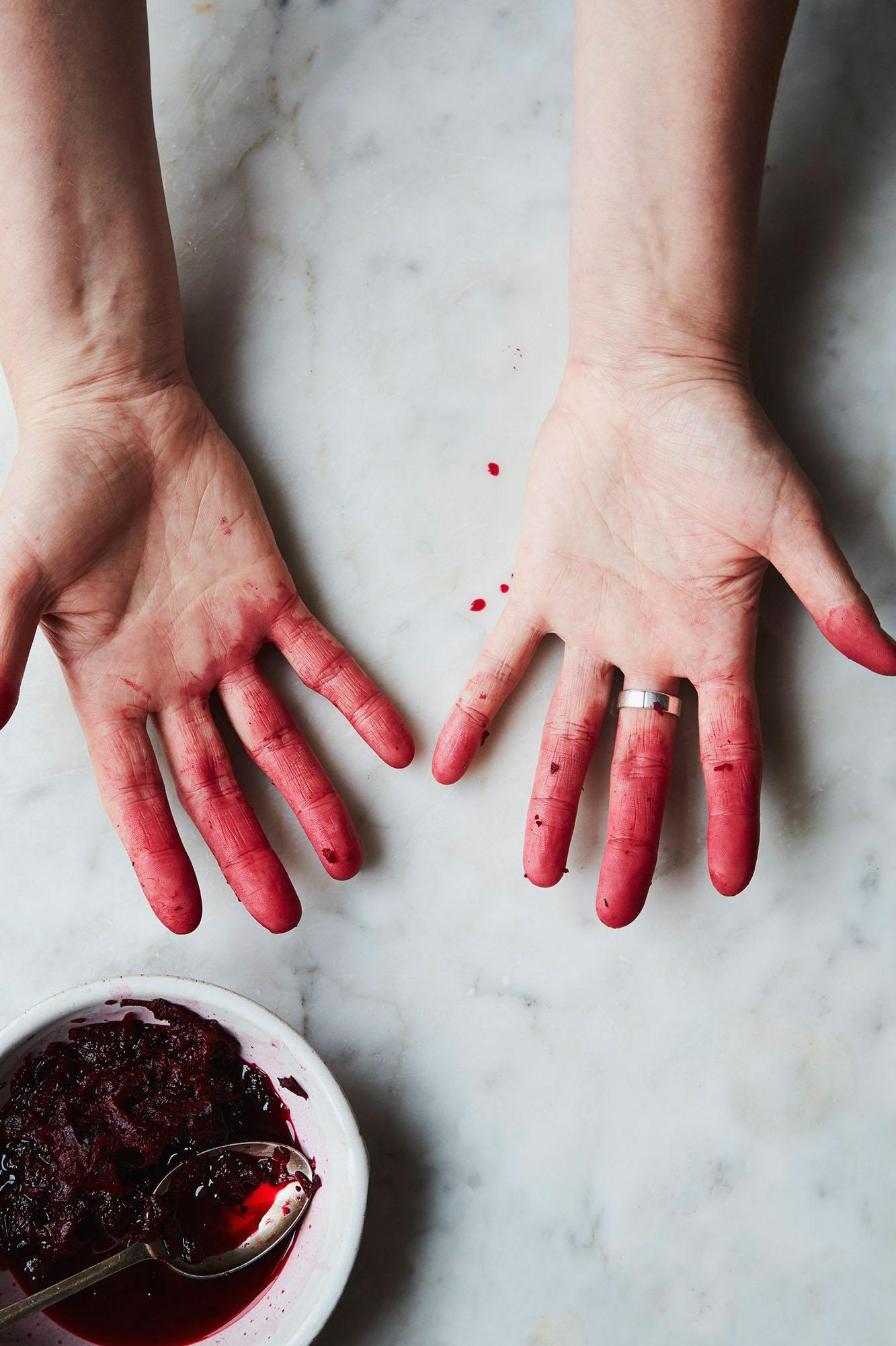 Hands covered in dark reddish-purple substance.