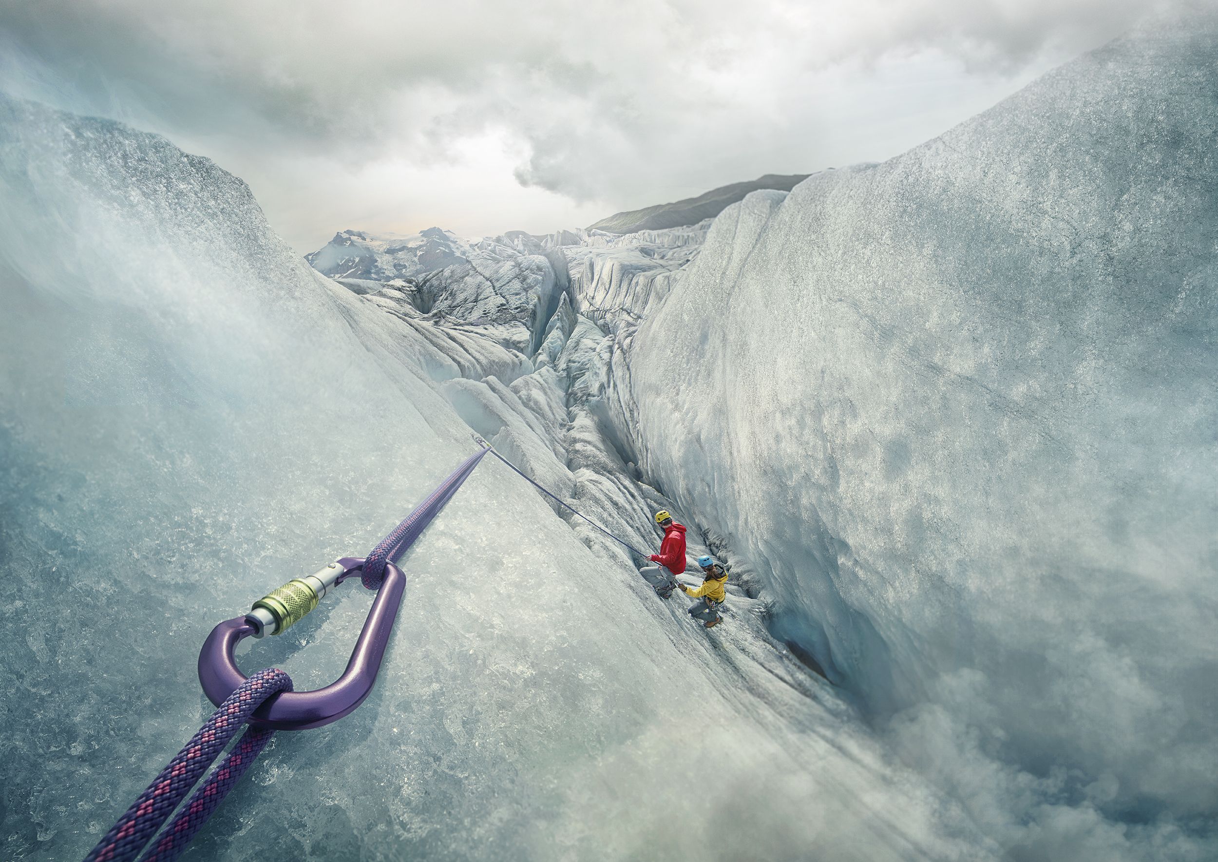 Two people wearing climbing gear and helmets are on a steep rock face with a purple and red climbing rope in the foreground.