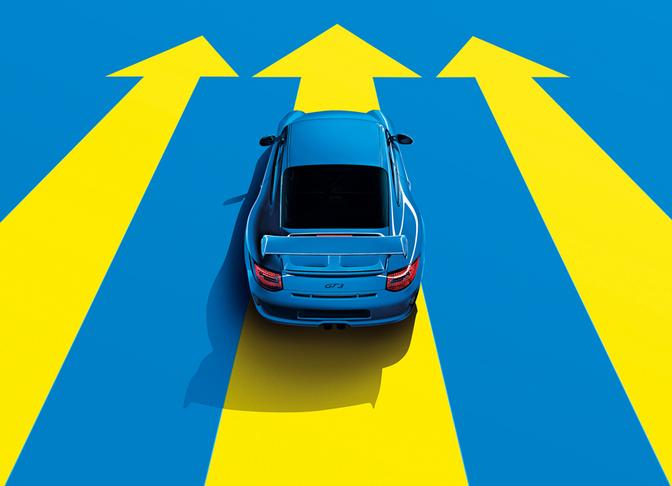A blue sports car is driving on a road with multiple yellow arrows pointing in different directions.