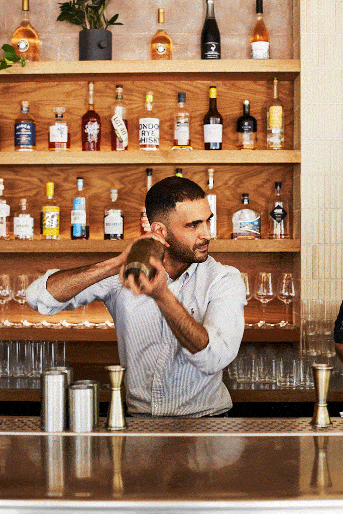 A bartender shaking a cocktail in an upscale, modern bar.