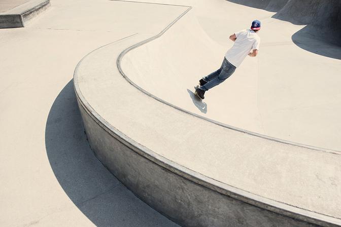 A skateboarder performing a trick on a concrete ramp in a skate park.