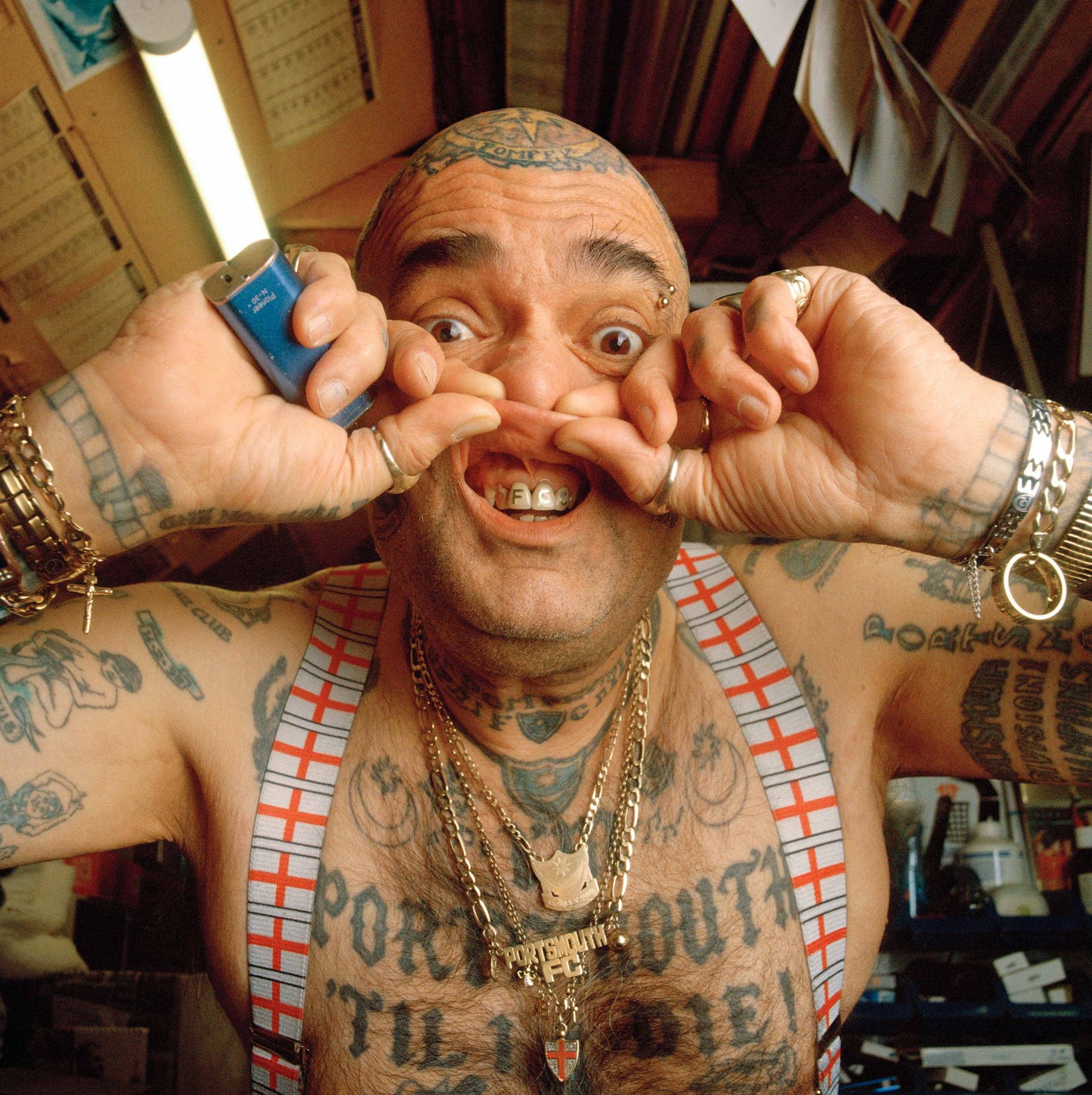 A man makes a provocative face while wearing a football jersey and a chain.