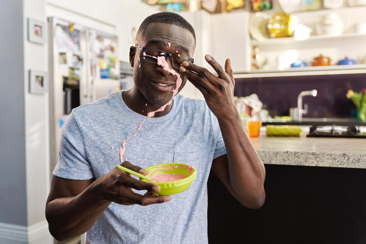 A man holds a green bowl containing pink substance.