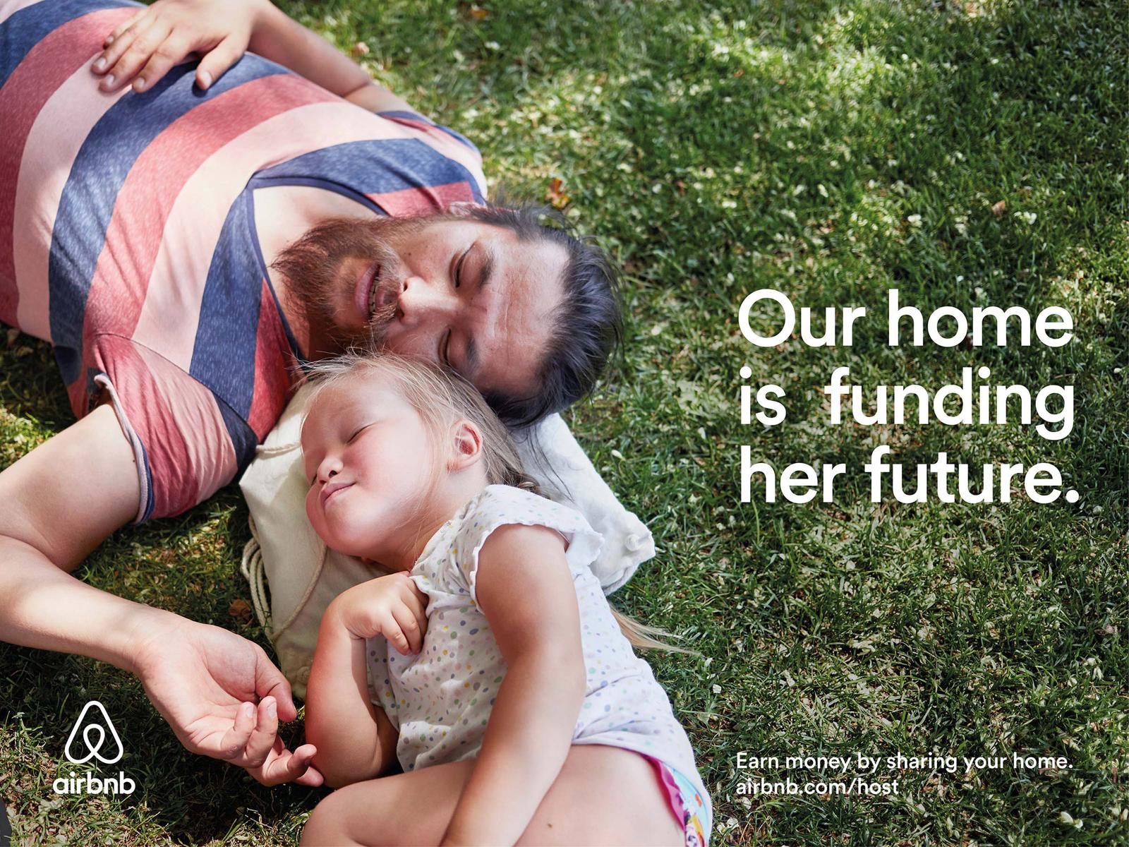 A man and a young girl are sleeping on a grassy lawn, surrounded by trees and a few flowers.
