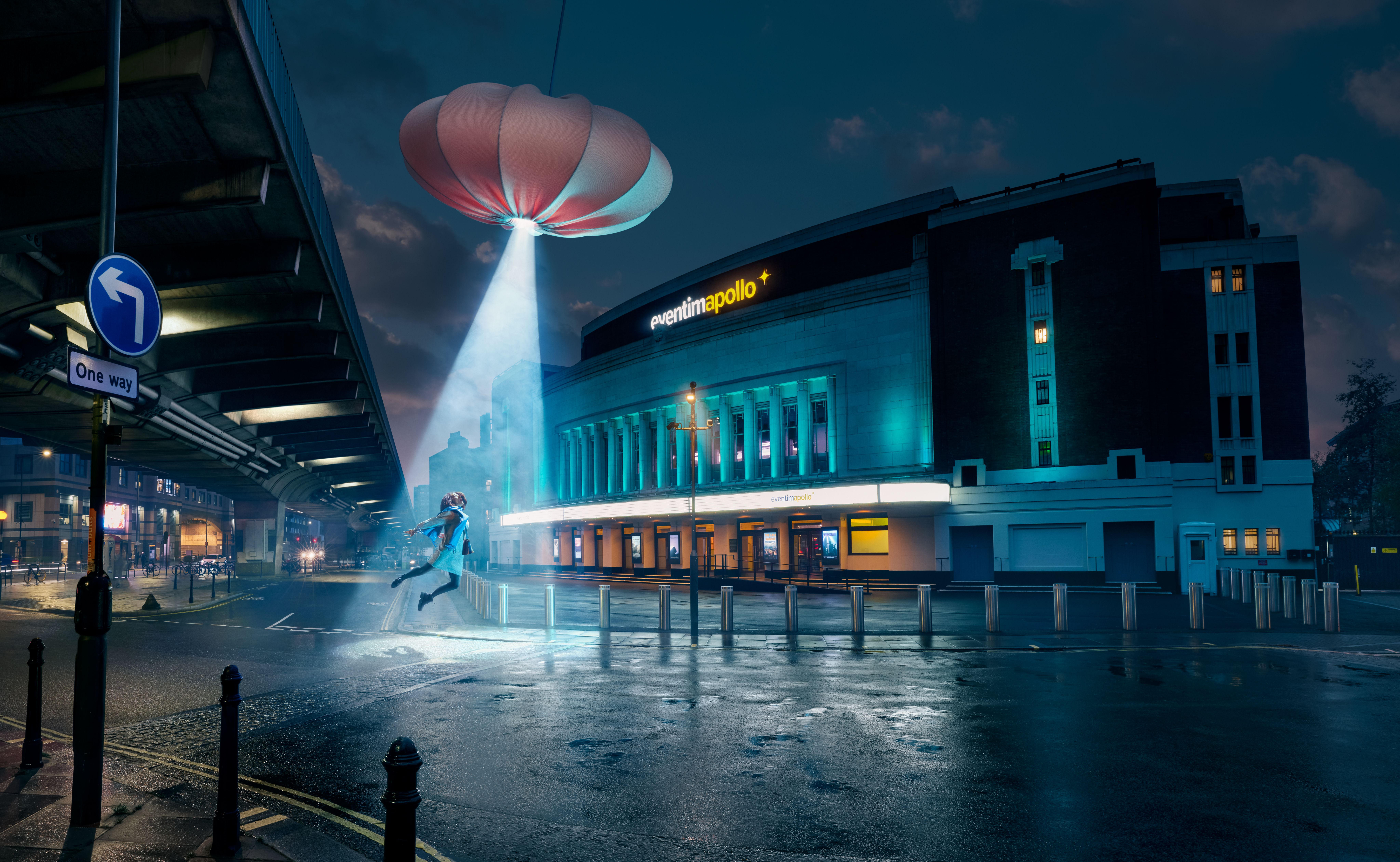 A person flying towards a hovering object in a futuristic city outside hammersmith apollo with a ufo abducting person in light