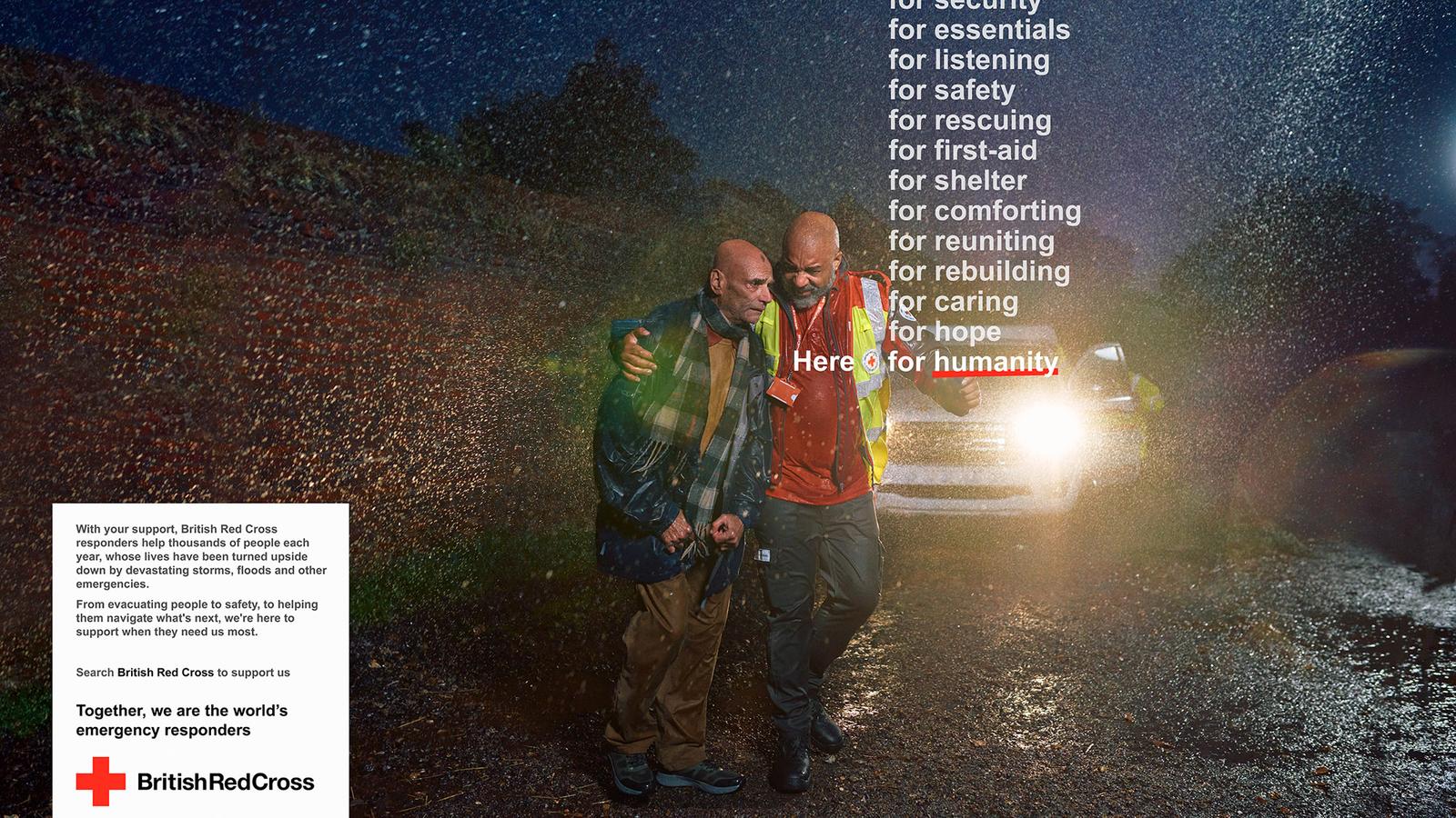 Two men in rain gear and high-visibility vests, one with a red lanyard, standing in front of a car in the rain, with a red and white British Red Cross logo in the corner.