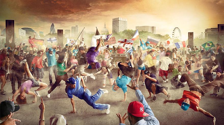 A large crowd of people dancing in the street, with some holding flags and others wearing casual clothing such as t-shirts, shorts, and sneakers.