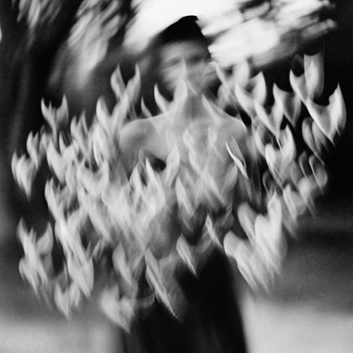 A person in a dark, abstract, and distorted environment, with a face that is not clearly visible, surrounded by a swirling, ethereal, and dreamlike atmosphere.