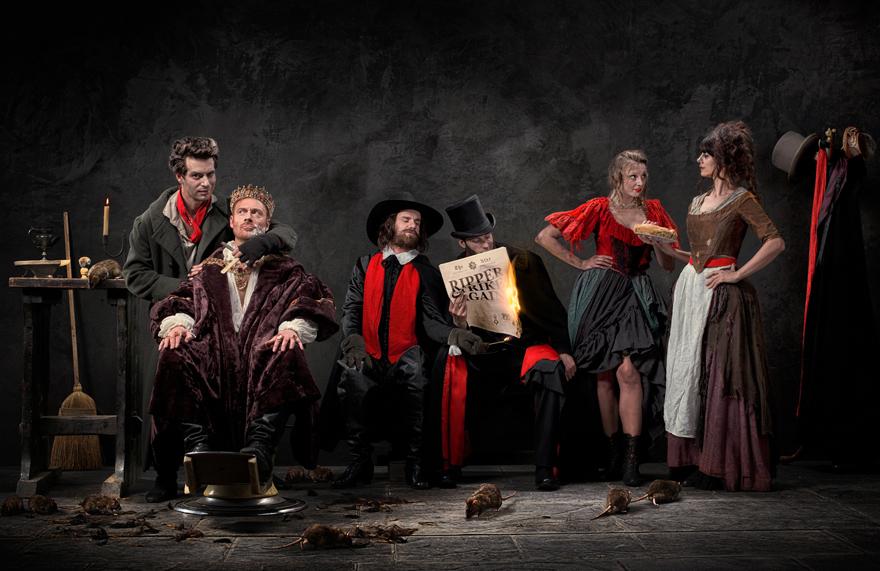 A group of people in Victorian-era clothing, surrounded by rats and a dark, ominous atmosphere.