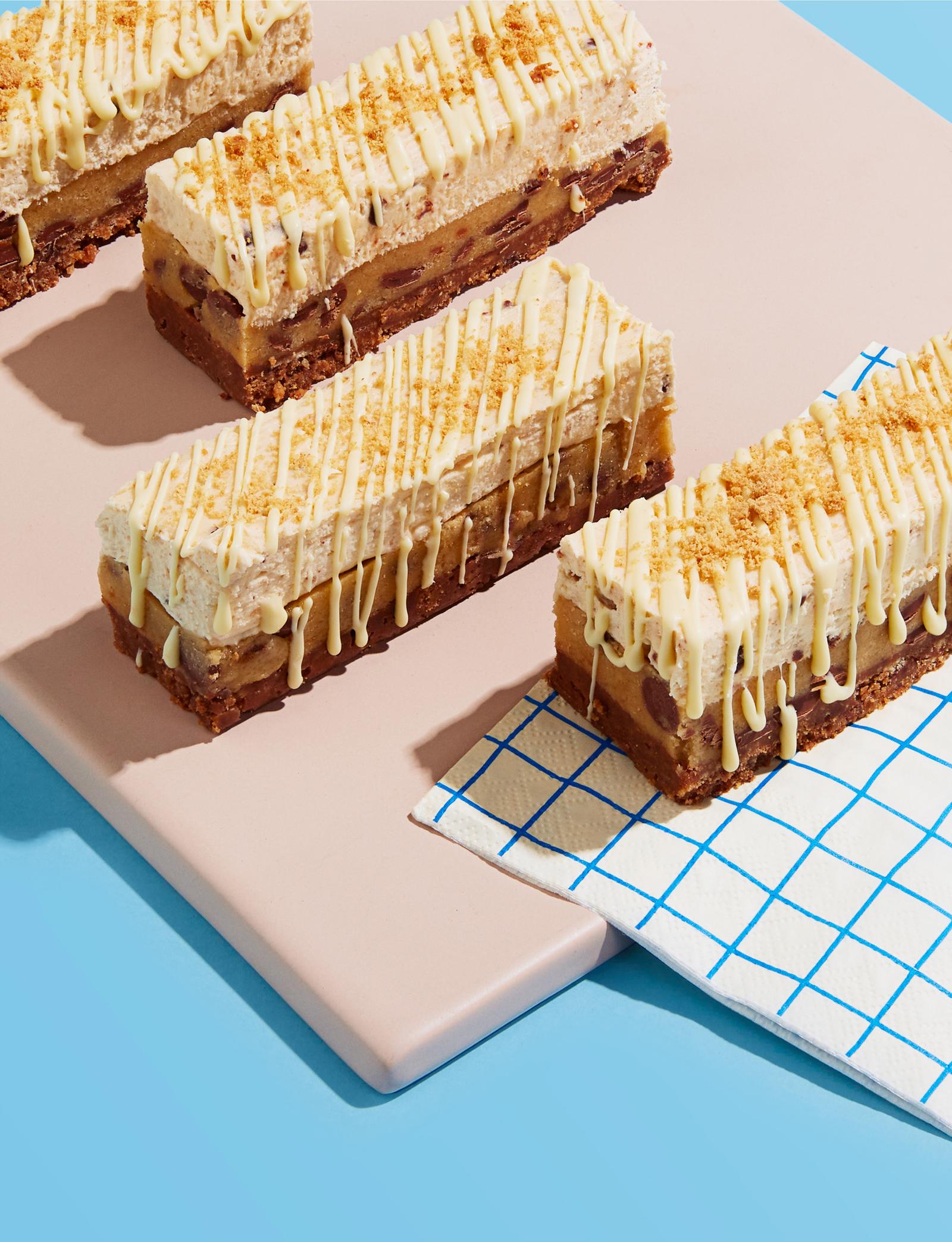 A selection of white chocolate and cookie bar desserts on a pink surface, with a blue and white checkered napkin in the background.