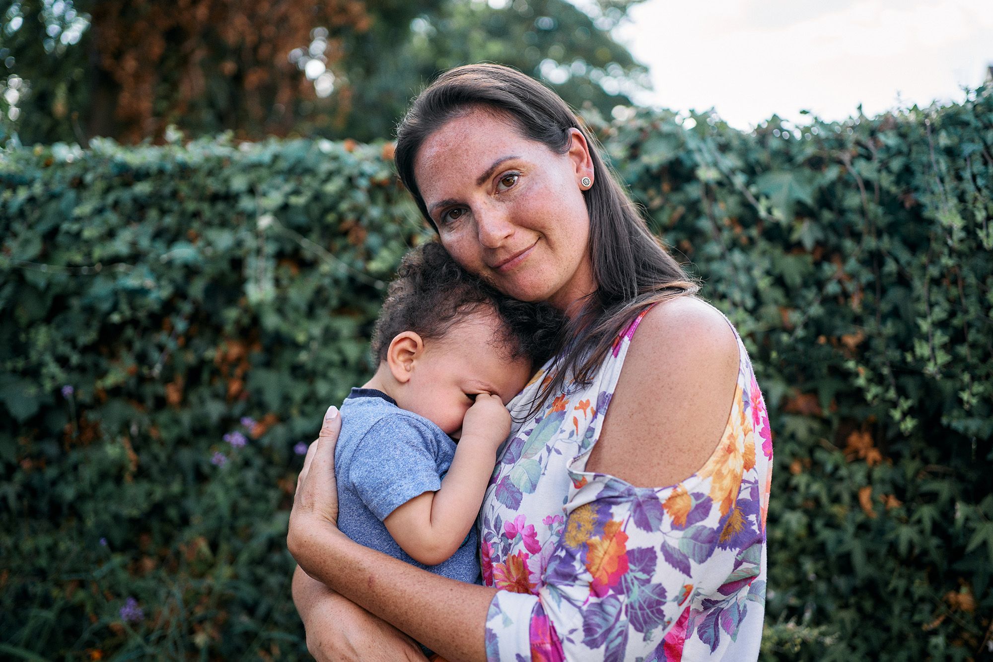 A woman holding a young child, both smiling and embracing each other.