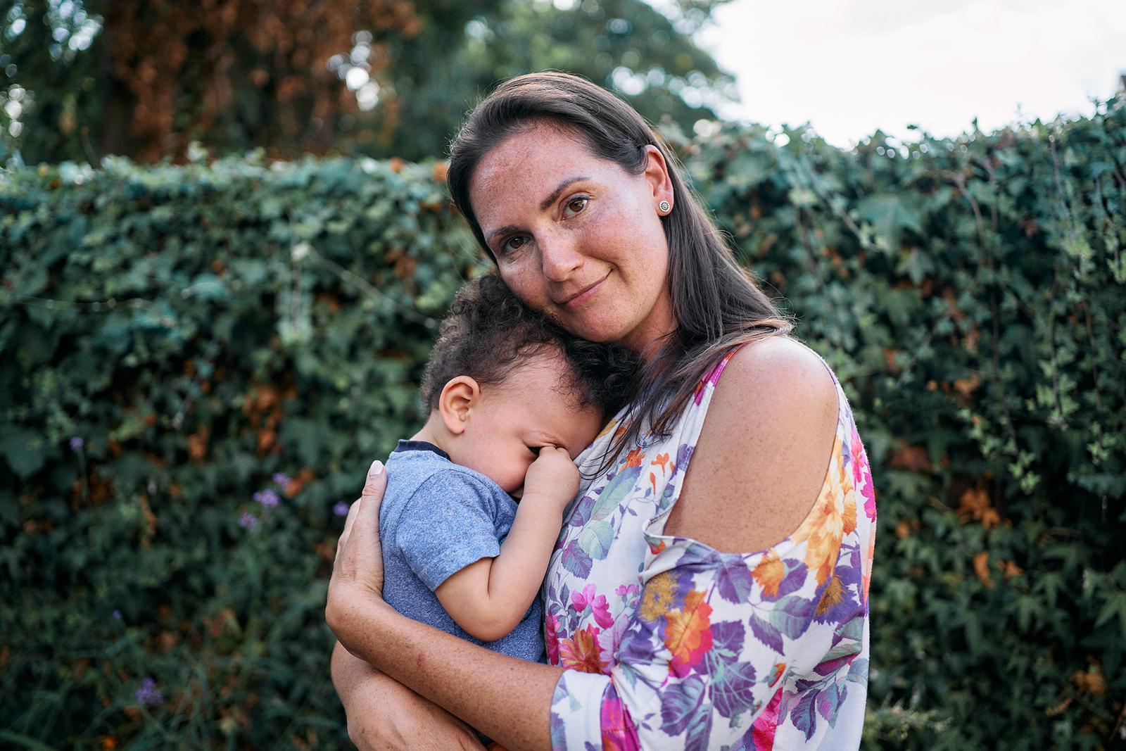 A woman holding a young child, both smiling and embracing each other.