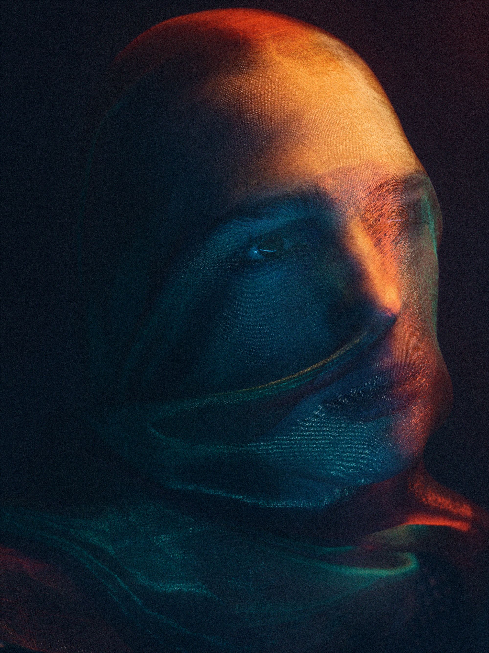 A person wearing a full-face mask, with only their eyes visible, in a dark and ominous setting.