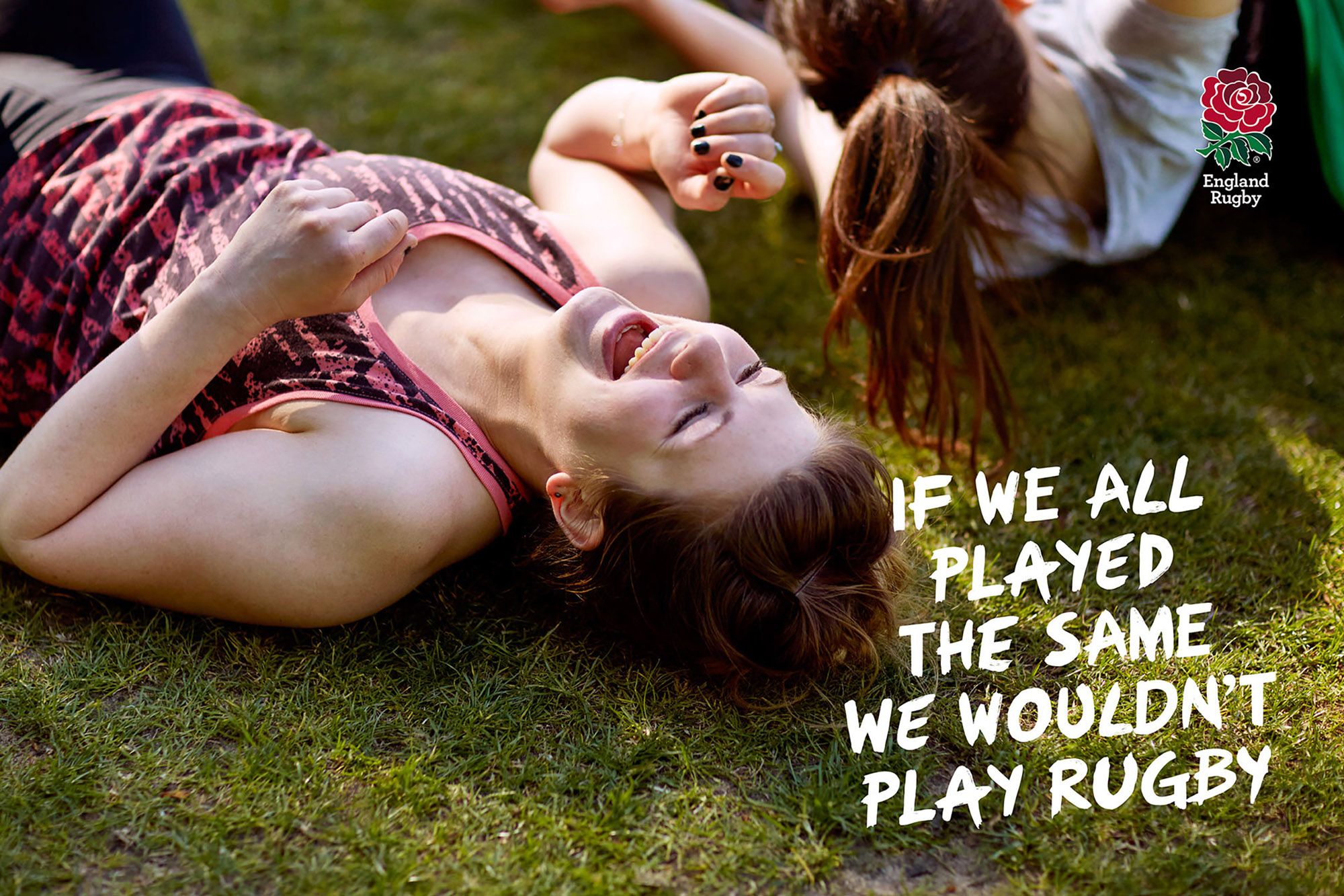 Two women lying on the grass, laughing and having fun.