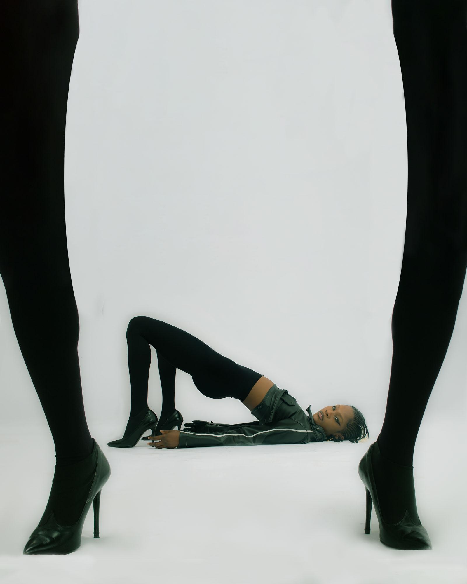 A woman lies on the floor with two pairs of legs nearby.