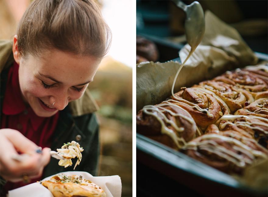 A woman is eating a pastry with a fork, with a tray of pastries in the background.