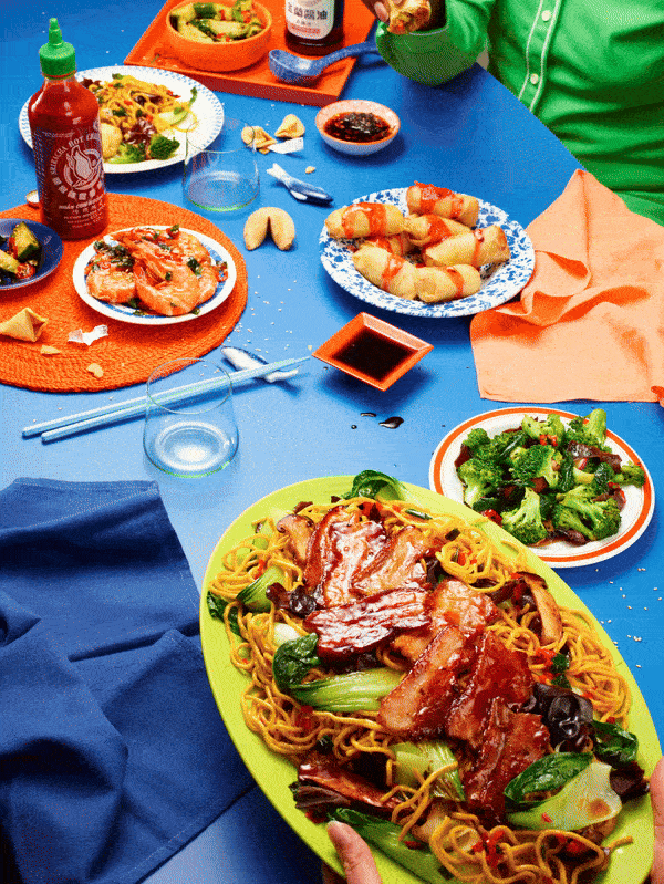 A table set with Chinese dishes like noodles and dumplings, along with Chinese decorations.