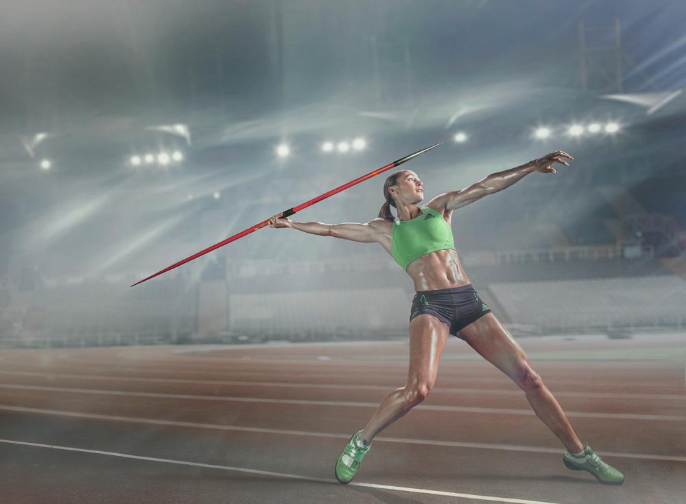 A woman throwing a javelin on a track and field stadium.
