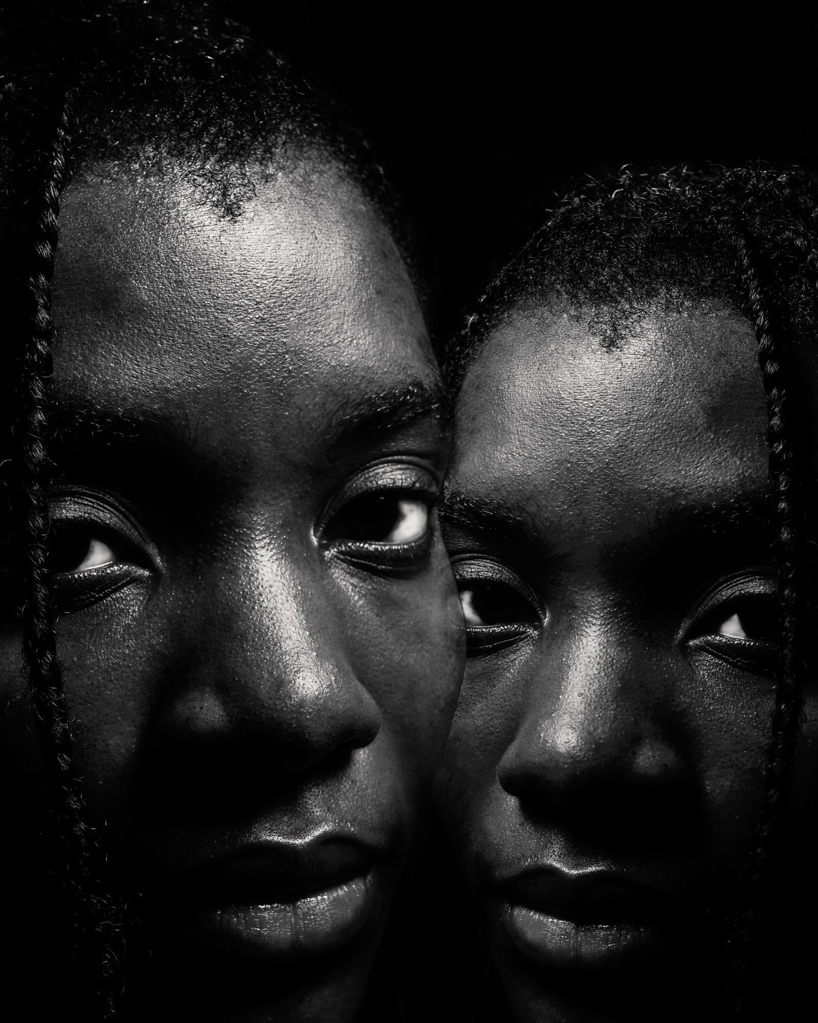 Two young black men with braided hair and facial hair, looking directly at the camera with a serious expression.