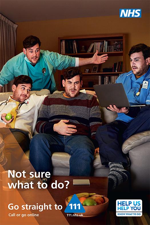 Three men, one in a nurse's uniform, one in a doctor's coat, and one in casual clothes, sitting on a couch, with a laptop and a bowl of fruit in the background.
