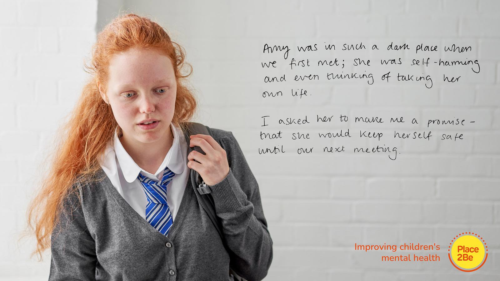 A young girl with red hair stands in front of a white wall displaying a quote and a Place2Be logo.