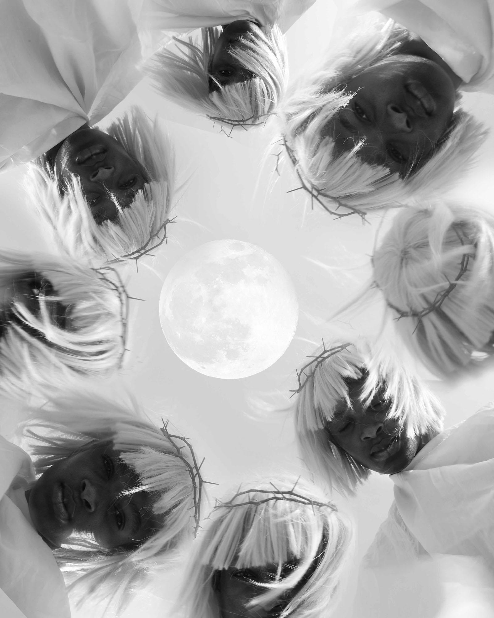A group of people in white robes with their faces obscured, surrounded by a full moon and a crown of thorns.
