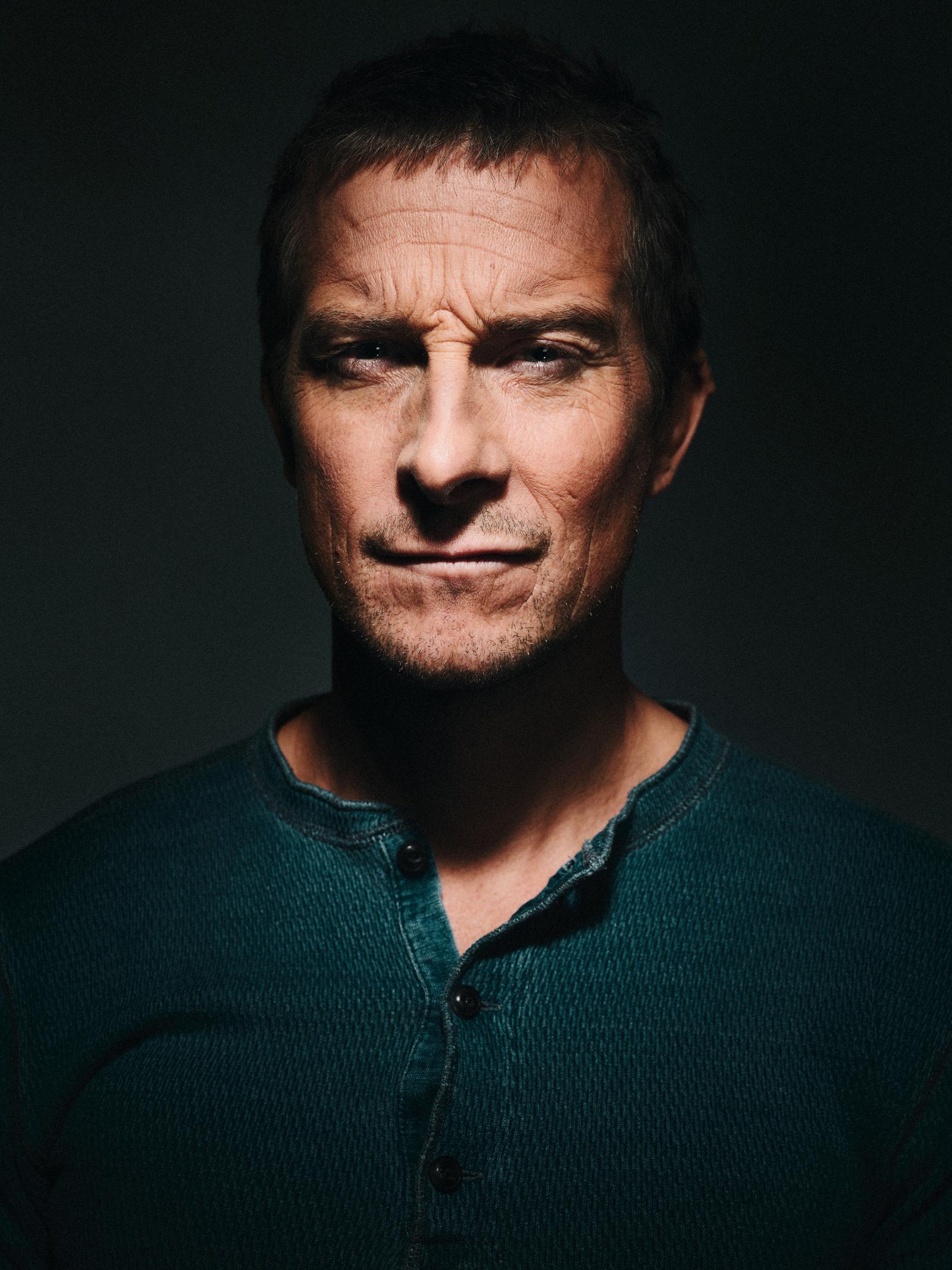 A man with a serious expression, wearing a dark green sweater with a subtle texture.