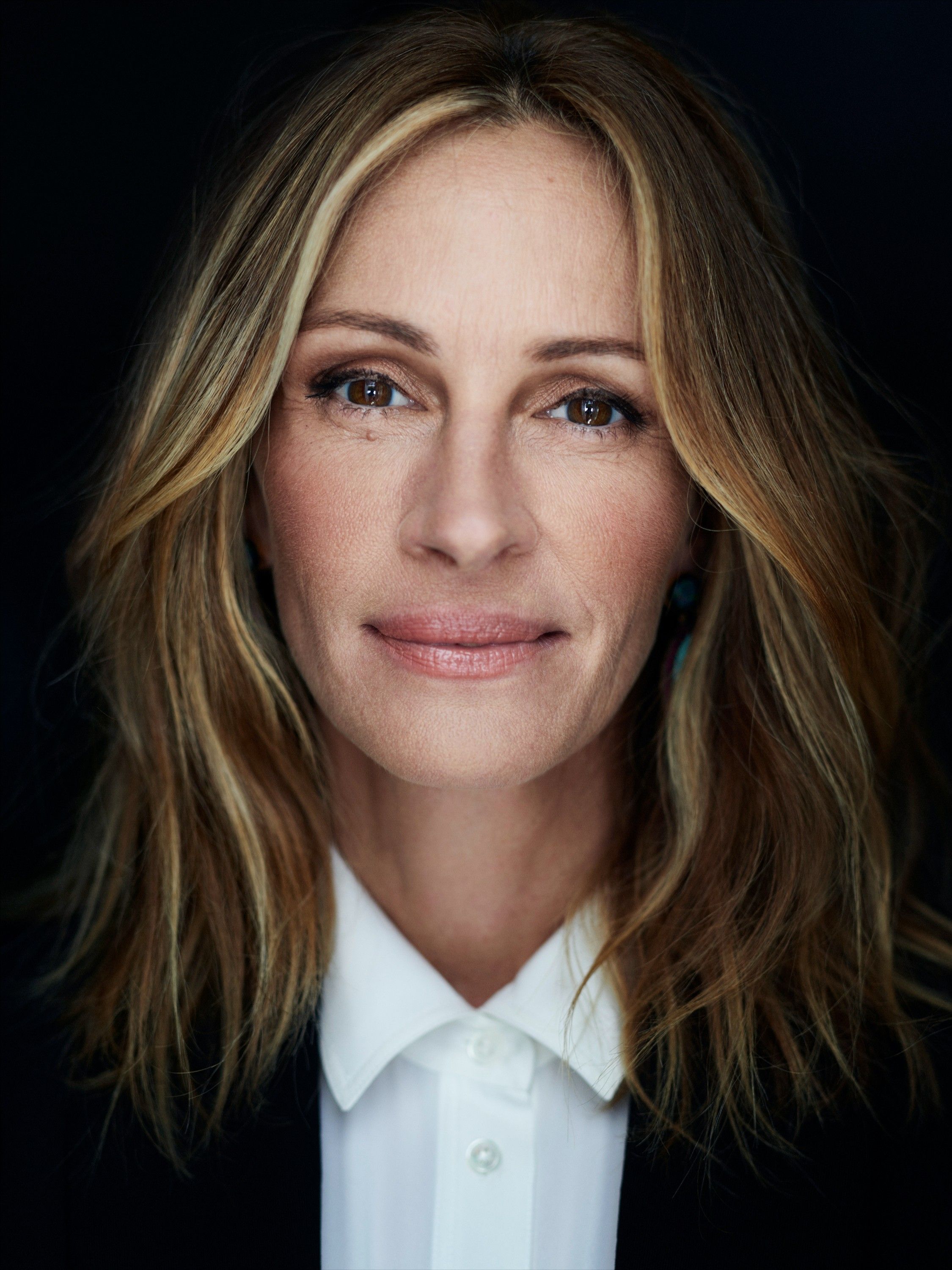 A portrait of a woman with long, blonde hair and a white, collared shirt, possibly a business or professional setting.