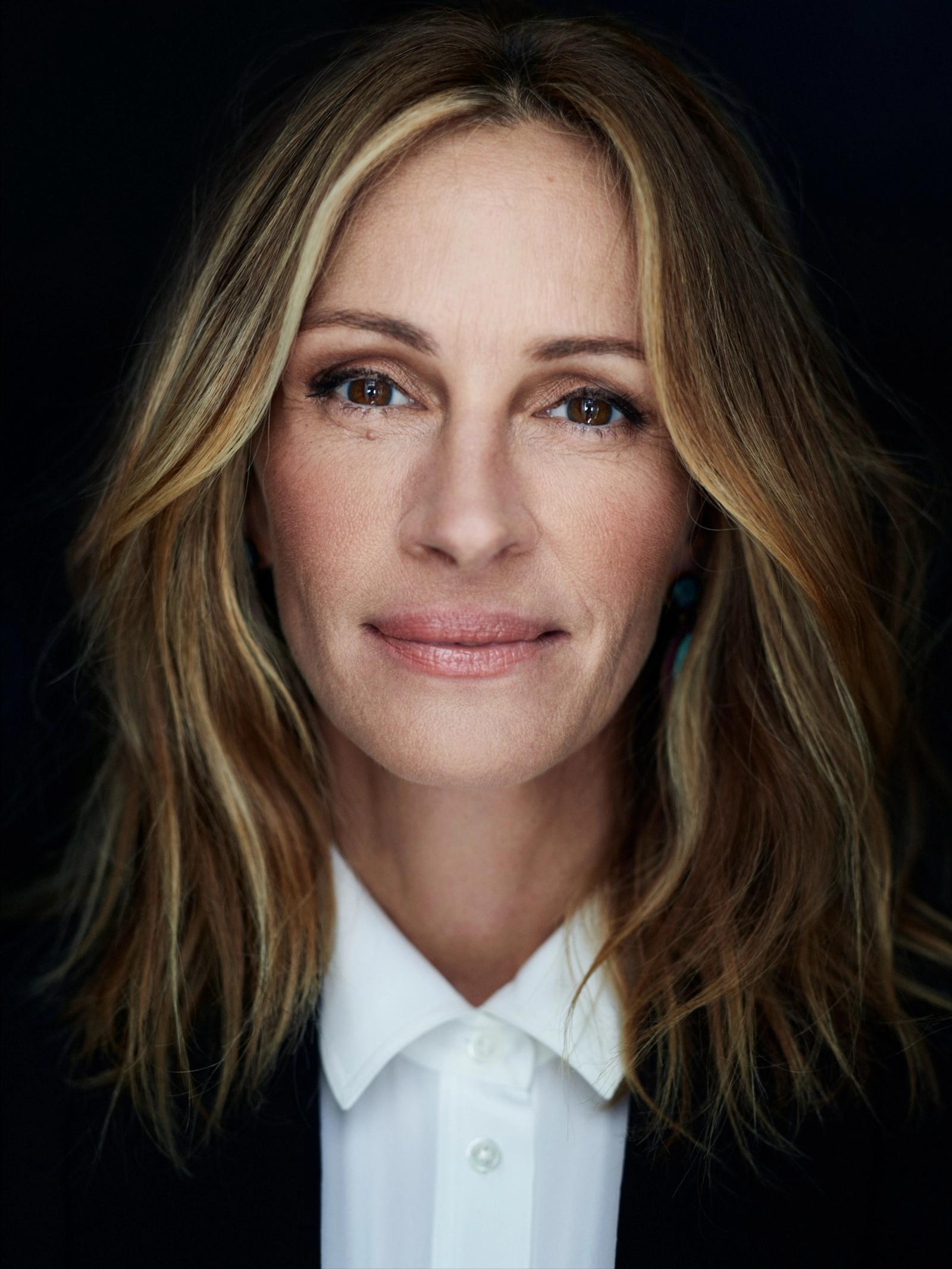 A portrait of a woman with long, blonde hair and a white, collared shirt, possibly a business or professional setting.