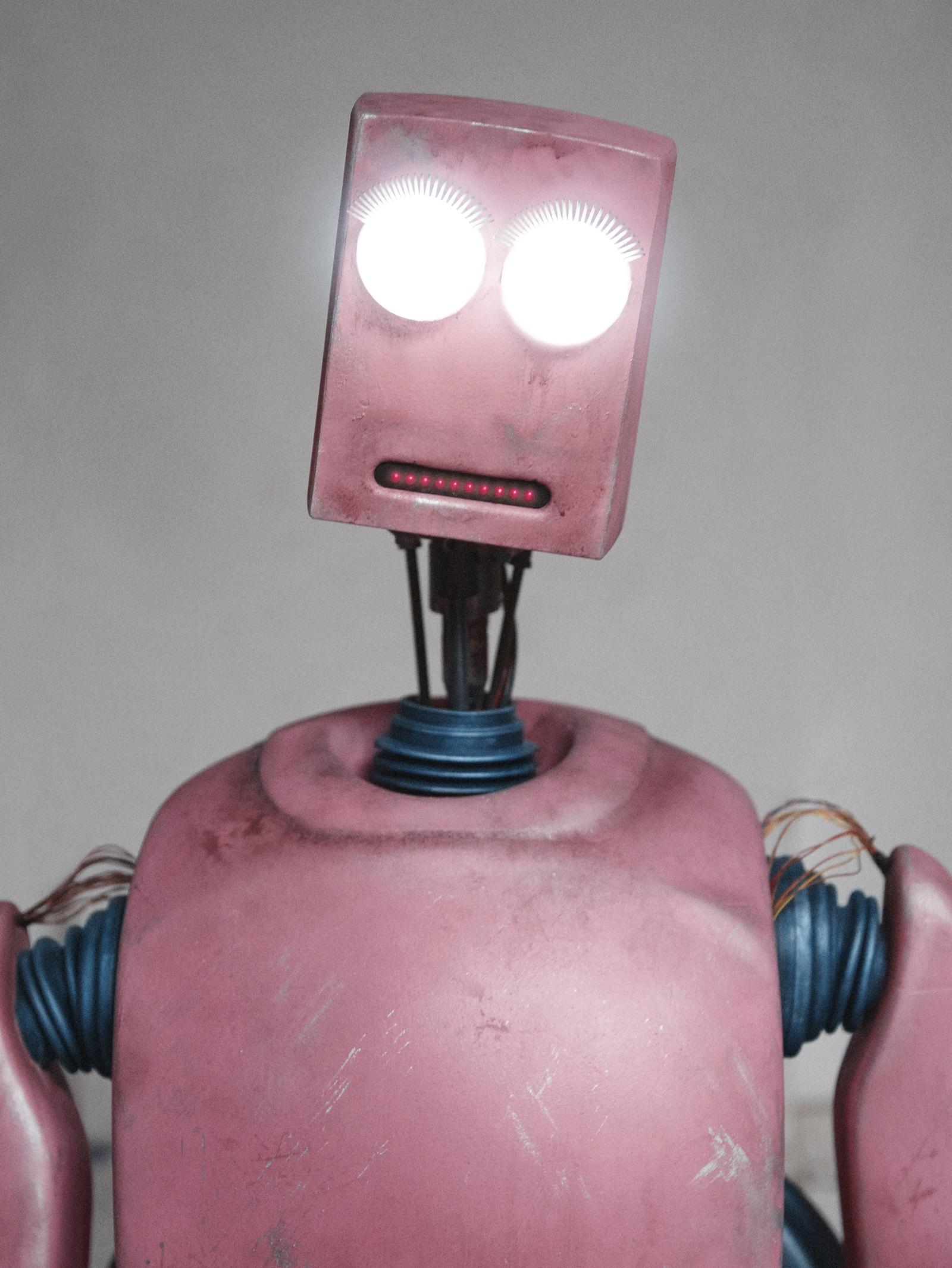 A pink, distressed robot-like figure with a square head and glowing eyes, wearing a metallic, industrial-style full-body suit.