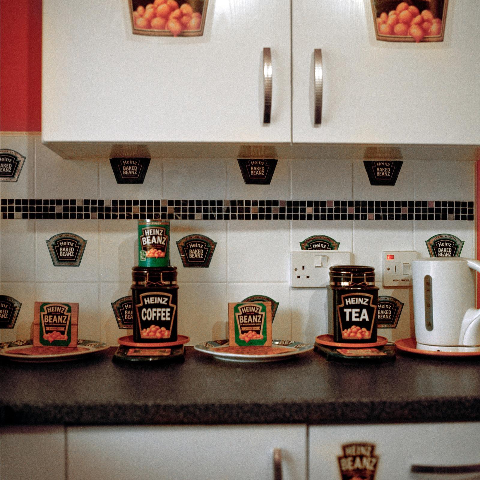 A kitchen counter with food items, a coffee machine, coffee pot, coffee cup, and a plate of biscuits.