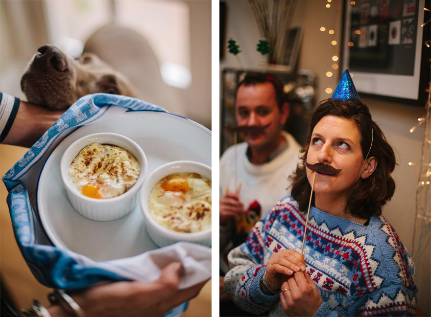 A person is holding a tray with two ramekins of baked eggs, with a dog's head in the background.