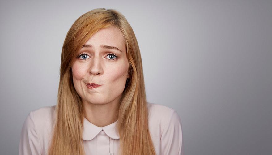 A woman with long, straight blonde hair and a white, collared shirt with a subtle, muted expression.