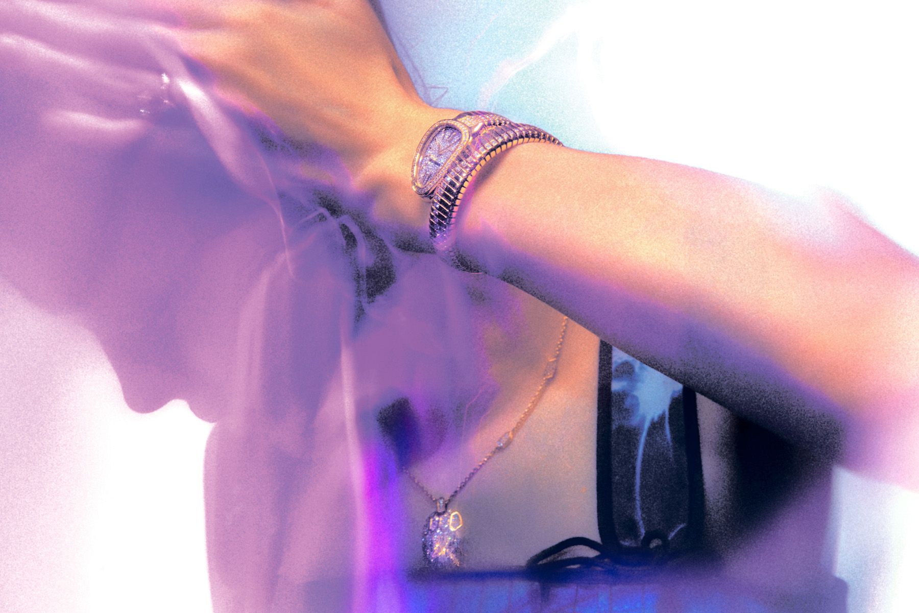 A person wearing a gold chain and a diamond-encrusted watch on their wrist, with a subtle hint of a tattoo on their neck.
