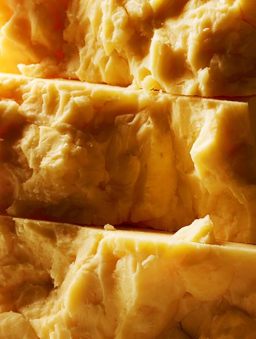 A close-up of a block of yellow, crumbly cheese.